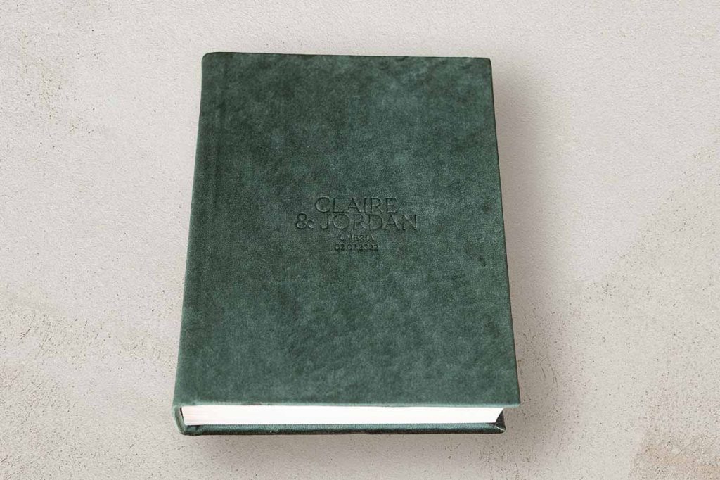 Portrait photo album for wedding photos with a velvet cover in a emerald green colour and custom lettering. Green wedding colour theme.
