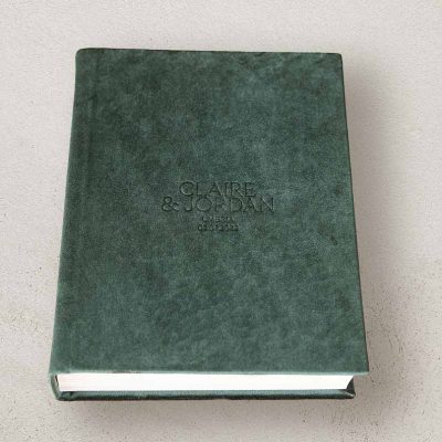 Portrait photo album for wedding photos with a velvet cover in a emerald green colour and custom lettering. Green wedding colour theme.